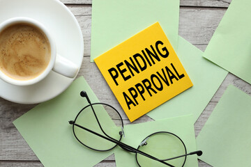 colorful note paper with pending approval text pinned to wood texture background and glasses
