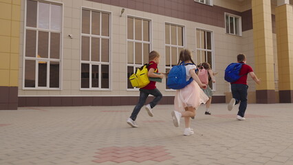 child schoolchildren with backpacks run lesson. cheerful team child girls boys run school. happy childhood student. teamwork. group children run classroom school bags backs. laughing grade students