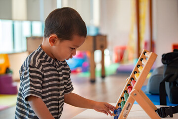 Asian little child playing with educational toys, learning shapes, arithmetic and colors at home,...
