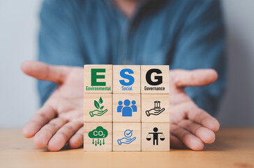 Businessman hand give  ESG wording on wooden cube block for sustainable organization development...