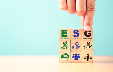 Businessman assemble ESG wording on wooden cube block for sustainable organization development and...