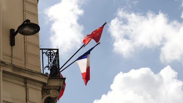 Two flags wave proudly atop a stunning European-style building in Asia, representing France and China's international partnership in Paris - Champs-Elysees