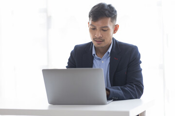 Handsome young business asian man using digital laptop at Busy elegant bearded adult company director, checking the company finances, at the office.