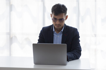 Handsome young business asian man using digital laptop at Busy elegant bearded adult company director, checking the company finances, at the office.