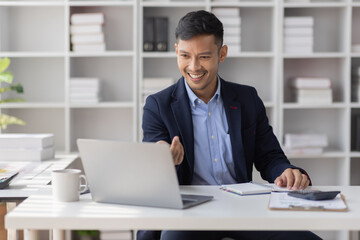 Obraz premium Handsome young business asian man using digital laptop at Busy elegant bearded adult company director, checking the company finances, at the office.