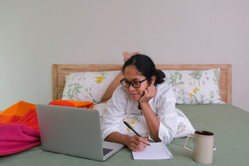 A woman lying on her stomach while working on a laptop