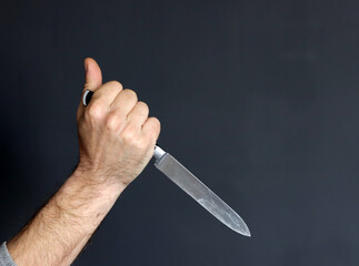 Man's hand holding a knife with blood on a black background. Domestic violence Murder Violence...