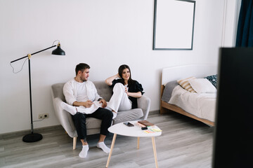Smiling couple having discussion on sofa
