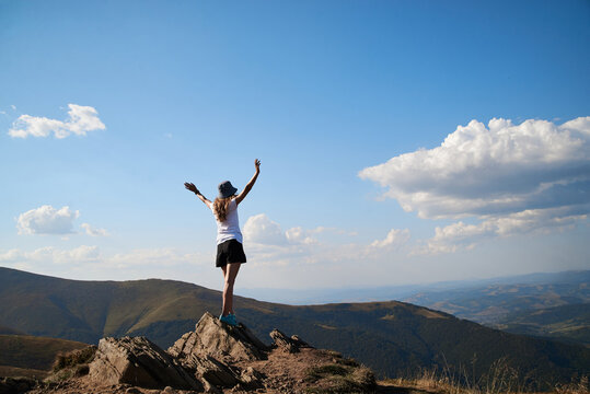 Young women standing on rock on top of the mountain. Feeling happy and free. Natural landscape in summer. Sunny rural scenery. Nature protection concept. Breathtaking mountain view.On top of the world © Natalia