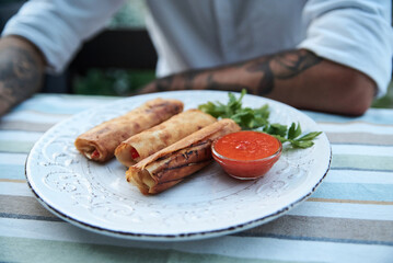 Close-up picture of fancy restaurant dish on white plate served on table. Young man having dinner lunch in cafe. Delicious ukrainian vegetarian food. Traveling and tourism entertainment.