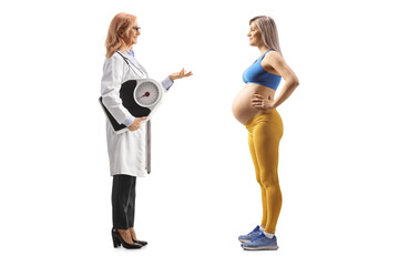Full length profile shot of a female doctor holding a weight scale and talking to a pregnant woman in sportswear