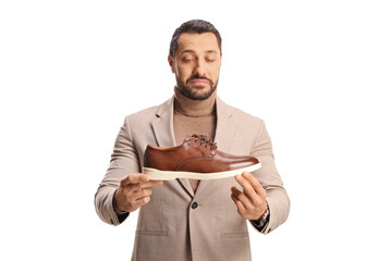 Young man holding a brown leather shoe and looking at it