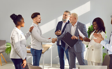 Business group applauding partners during meeting in office. Coworkers applauding to onfident handshaking businessmen shaking hands finishing successful meeting, good job results