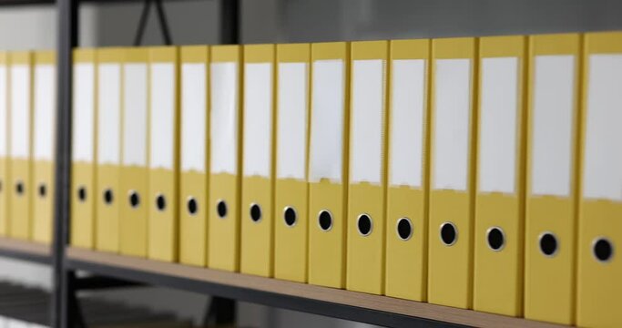 Yellow folders with materials and documents are arranged on shelves. Storage of business documentation and service archive
