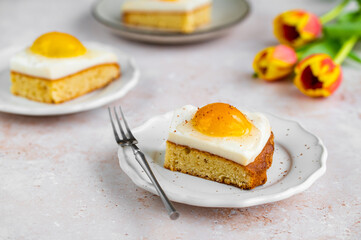 Homemade German Fried Egg Cake Spiegeleierkuchen with apricot and milk pudding on a light background with tulips. Traditional Easter Dessert. Festive Easter food.