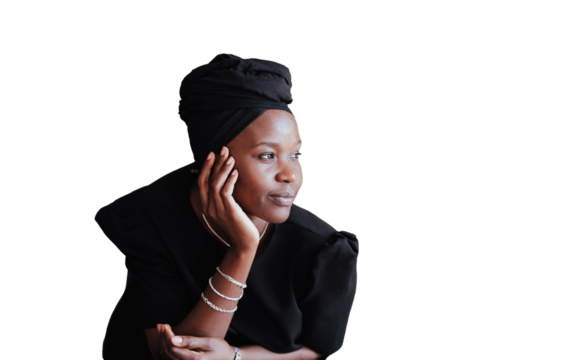 Pensive African girl in black turban and traditional dress looks aside leaning on couch against transparent background with empty space. Thoughtful young adult woman relaxing home. Muslim female