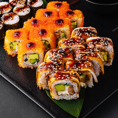 Big set of rolls with wasabi and pickled ginger on stone serving board