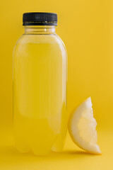 Bottle of fresh lemon juice on yellow background
