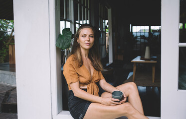 Calm woman with coffee on windowsill