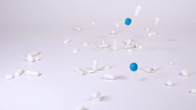White and blue pharmaceutical products, tablets, pills and capsules falling down against white background. Concept of healthcare, medicine, pharmacy and drugs. Treatment and prevention of diseases. 4K