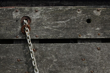 A close-up of a chain attached to a wooden fence
