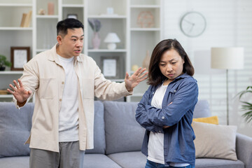 Family quarrel, asian couple man and woman yelling at each other, family conflict, asians at home standing angry in living room.