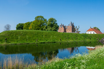 Fototapeta na wymiar Captivating view across the moat water over the dike to Slot Loevestein Castle and its rich history. The fortress is the most famous in the Netherlands.