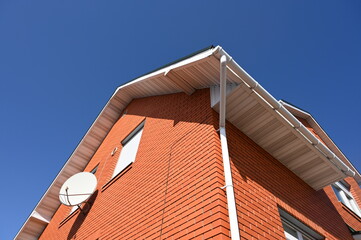 The end of a private house made of red brick with a satellite dish.