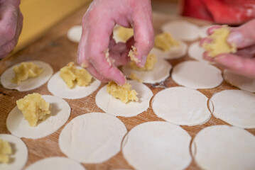 a woman prepares homemade dumplings with potatoes on a wooden board. Homemade food.