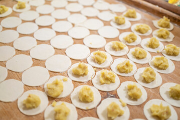 a woman prepares homemade dumplings with potatoes on a wooden board. Homemade food.