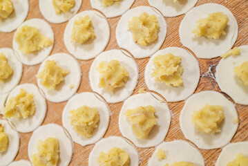 a woman prepares homemade dumplings with potatoes on a wooden board. Homemade food.