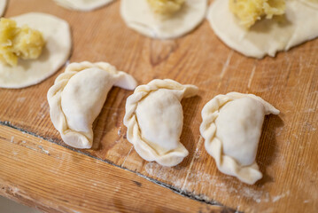 Fototapeta na wymiar a woman prepares homemade dumplings with potatoes on a wooden board. Homemade food.