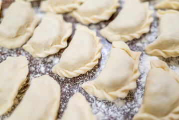 a woman prepares homemade dumplings with potatoes on a wooden board. Homemade food.