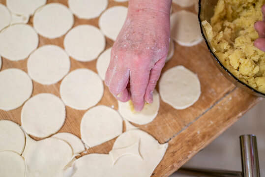 a woman prepares homemade dumplings with potatoes on a wooden board. Homemade food.