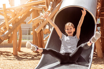 Happy Child Sliding Down Slide Having fun on Children Playground. Joyful Kid Girl enjoying playing...