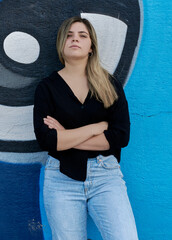 Blonde girl with crossed arms and a defiant look.