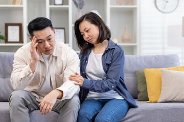Family psychological support, Asian couple sitting at home on sofa thoughtful, woman comforting and...