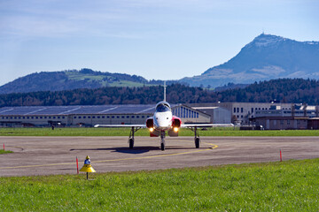 Red and white Northrop F-5E Tiger II fighter of Patrouille Suisse taxiing to hangar at Swiss Air...
