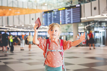 Little preschool girl at airport terminal. Happy child going on vacations by airplane. Smiling kid...
