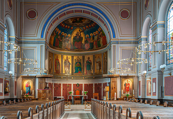 Copenhagen, Denmark - September 13, 2010: Colorfully painted apse of Sankt Angars Kirke, Catholic Church, seen from nave with benches. Natural light falls through windows. Altar upfront