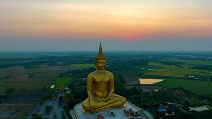 scenery sunset behind the great golden Buddha landmark of Thailand at wat Muang Ang Thong Thailand. .The largest Buddha statue in the world Surrounded by rice fields..colorful sky background.