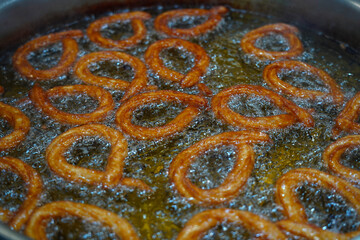 Turkish Dessert Churros Halka Tatli frying in hot oil. Turkish doughnuts or traditional ring sweet, yağda kızarmış halka tatlısı                 - obrazy, fototapety, plakaty
