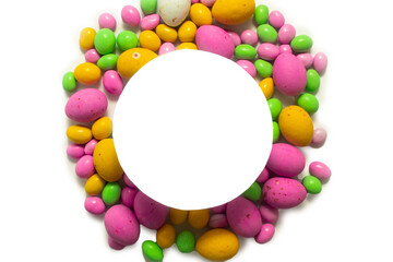 Multicolored dragees and chocolate eggs in the shape of a circle with space for text