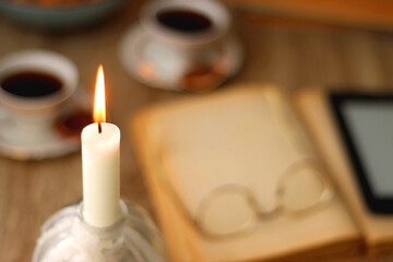 Books, reading glasses, e-reader, plate of chocolate pralines, bowl of cookies, cups of tea and lit...