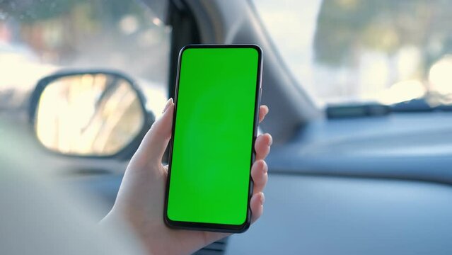 Close up of a woman's hand holding a mobile telephone with a vertical green screen in car chroma key smartphone technology cell phone street touch message display hand