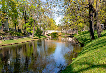 Stone bridge over Riga river canal in Riga central city park at sunny spring day, capital of Latvia. 