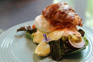 Croissant fresh sandwich with poached egg and vegetable on white plate