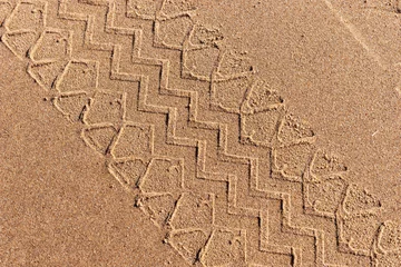 Schilderijen op glas Tire track on the beach. Tire footprint in the sand © kelifamily
