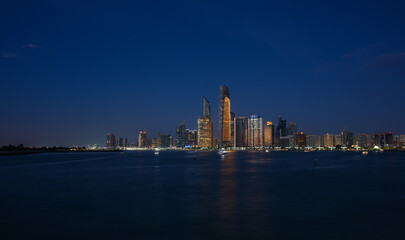 Fototapeta premium Abu Dhabi by night. Long exposure photo during the blue hour with the amazing skyline of Abu Dhabi. Travel to United Arab Emirates.