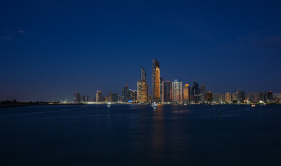 Fototapeta na wymiar Abu Dhabi by night. Long exposure photo during the blue hour with the amazing skyline of Abu Dhabi. Travel to United Arab Emirates.